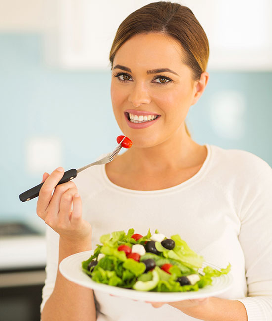 Happy employee eating a healthy Greek salad with tomatoes and olives
